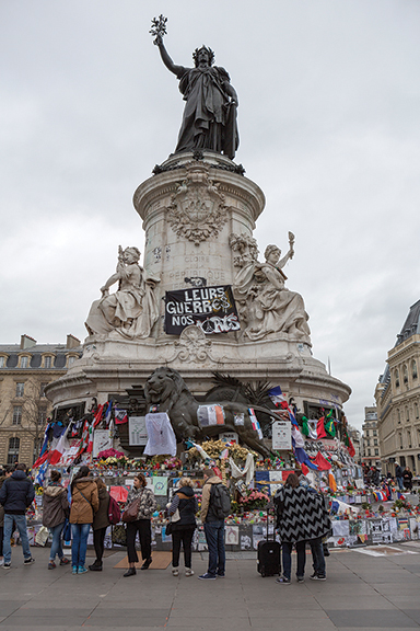 Paris, France - January 29, 2016: People mourn and stand in front of the memorial marking the terrorist attacks on 13 November 2015. Place de la Republique became the gathering spot to mourn the loss of life that occurred.